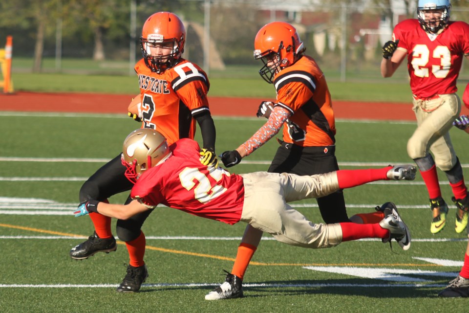 Hammarskjold's Jackson Merrill dive tackles Westgate's Rory Jeffers (2) while teammate Brendan Hall attempts to fend him off  on Thursday, Sept. 29, 2016 at Fort William Stadium (Leith Dunick, tbnewswatch.com). 