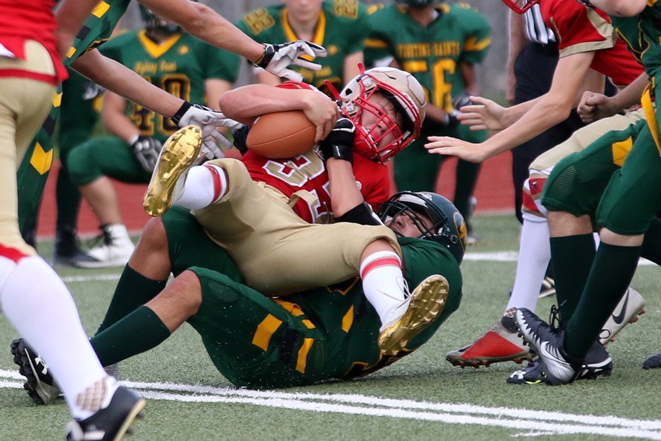 Hammarskjold's Dylan Halls is hauled down by a pair of St. Patrick defenders on Thursday, Sept. 19, 2019 at Fort William Stadium. (Leith Dunick, tbnewswatch.com)