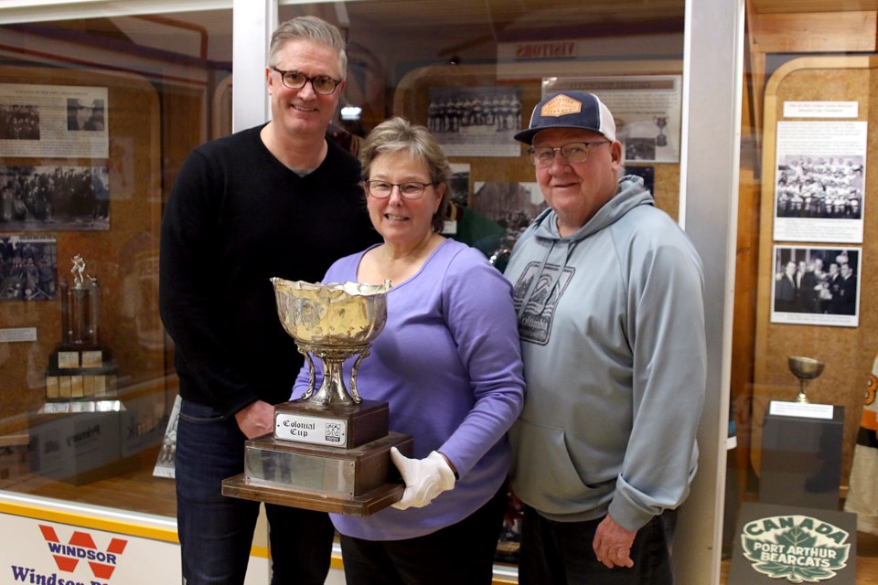 Tom Warden, a member of the 1992 Colonial Cup-winning Thunder Bay Thunder Hawks, Diane Imrie, executive director at the Northwestern Ontario Sports Hall of Fame, and Bill McDonald, who coached the 1992 squad, on Tuesday, Feb. 12, 2019 pose with the original trophy. (Leith Dunick, tbnewswatch.com)