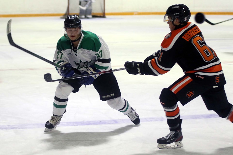 Thunder Bay's Michael Stubbs (left) flips the puck past Kam River's Trenton Morriseau on Friday, Nov. 13 at the Norwest Arena. (Leith Dunick, tbnewswatch.com)