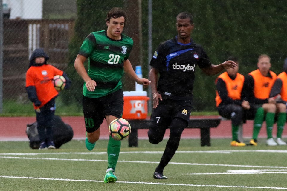 St. Louis' Troy Reeves (left) and Thunder Bay's Sullivan Silva chase down the ball in the rain on Wednesday, July 12, 2017 at Fort William Stadium (Leith Dunick, tbnewswatch.com). 