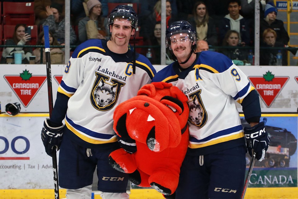 Lakehead captain Tyler Jette and forward Greg Smith, who scored the first goal, help collect the stuffed animals tossed on the ice in Lakehead's annual Teddy Bear Toss game on Saturday, Nov. 26, 2022 at Fort William Gardens. (Leith Dunick, tbnewswatch.com)