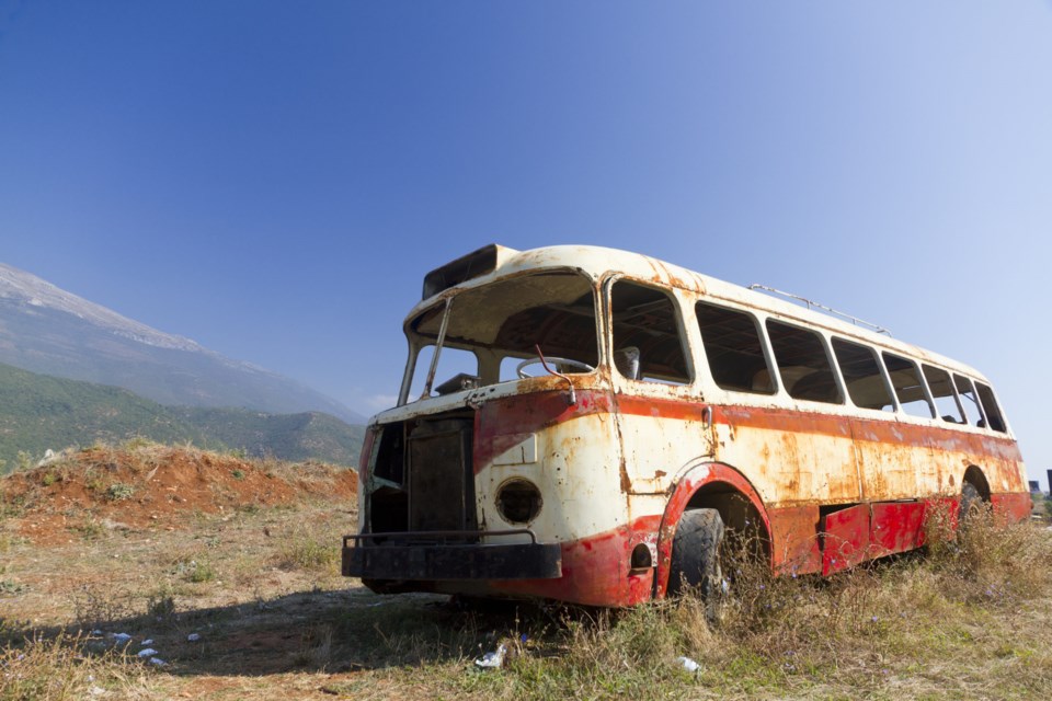 Stripped,Rusty,,Old,Abandoned,Red,Bus,Wreck,In,Arid,Mountainous