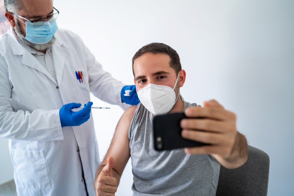 Doctor,Vaccinating,A,Young,Man,While,Taking,A,Selfie