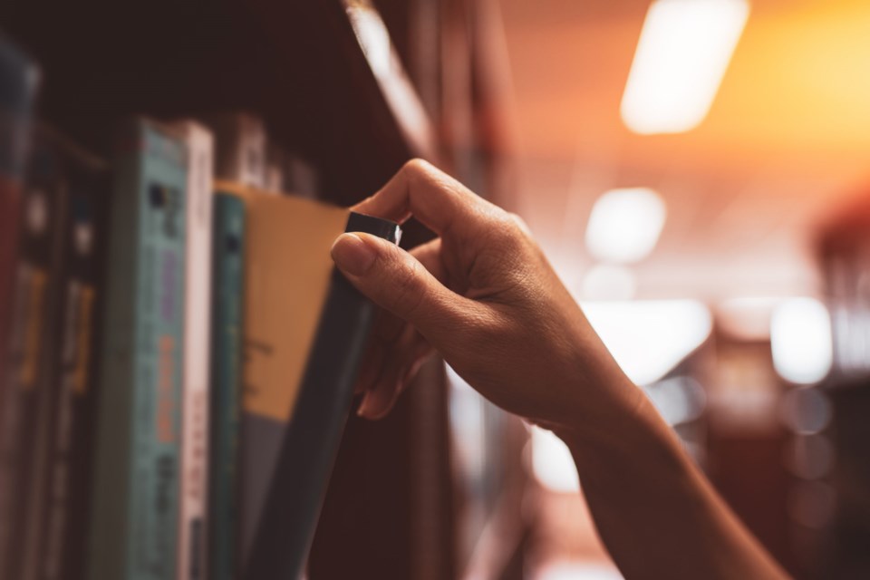 Image,Of,A,Hand,Selecting,A,Book,From,A,Bookshelf