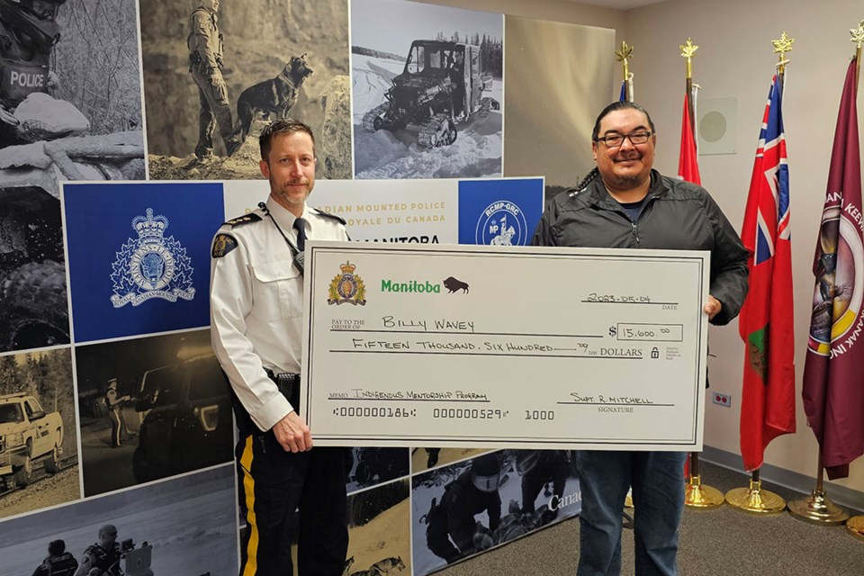 RCMP Manitoba North District commander Insp. Ryan Mitchell presents Billy Wavey of Split Lake with a cheque to support land-based education.