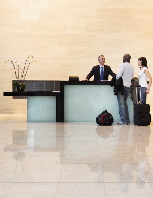 guests and worker at hotel front desk