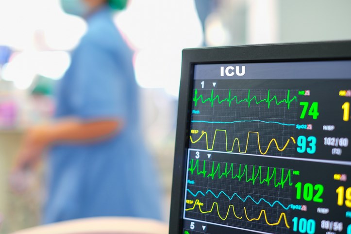 Heart rate monitor, patient and doctors in background in intensive care unit or emergency room - stock photo