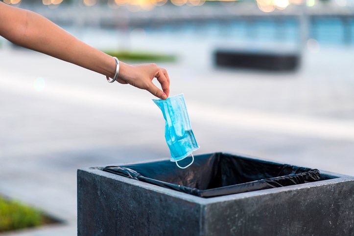 womans hand dropping medical mask into garbage can Stefan Tomic Getty Images