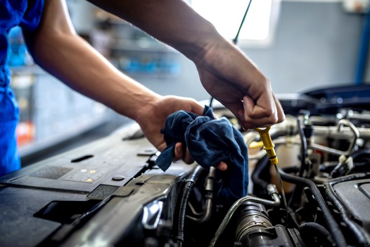 mechanic checking oil on vehicle engine stock photo