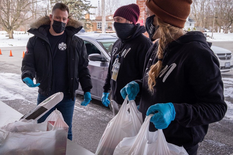 Tyler Hibbs (L), Josh Walsh (C), and Diana Slappendel (R) are seen at a drive-through grocery giveaway event put on by Open Arms Mission of Welland at the Wainfleet BIC Church on Jan. 30, 2021.