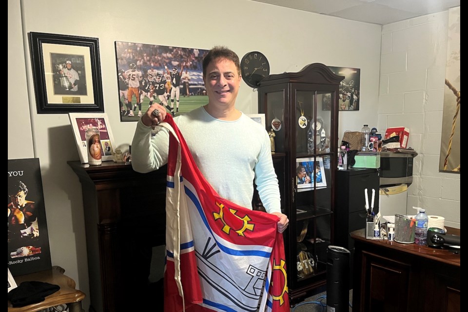 Giancola with the flag of Thorold in front of some memorabilia from his football career.