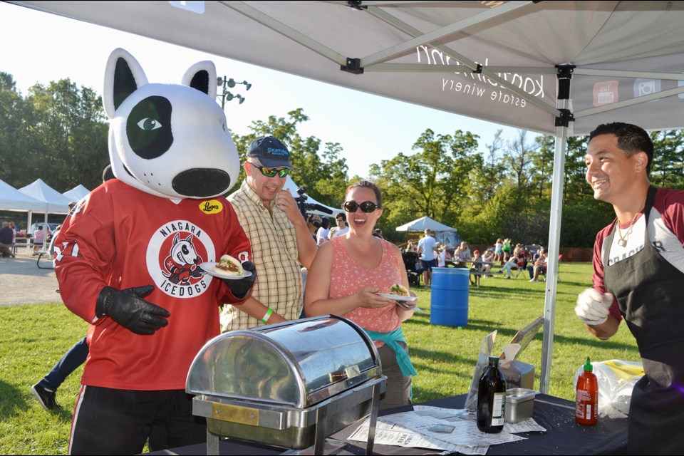 Abbey Solomon, Cracker Jack’s chef, serves a slider to a hungry Bones, Ice Dog mascot, at the Fonthill Lions Club’s Sliderfest Saturday. Gloria Katch/ThoroldNews