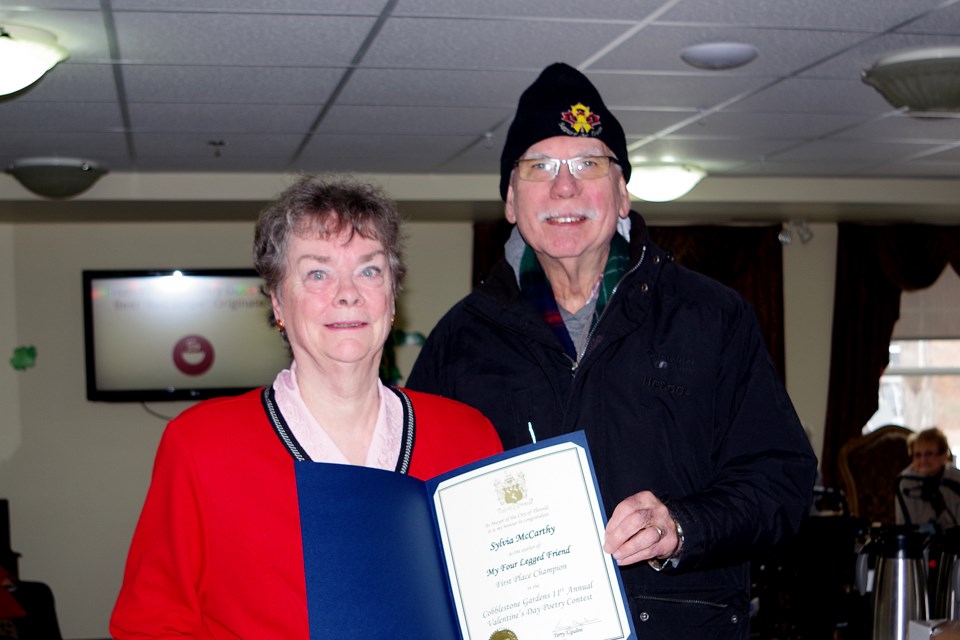 Councillor Fred Neale presents a mayor's certificate to Sylvia McCarthy, Grand Champion winner of the 11th annual Cobblestone Gardens Valentine's Day poetry contest. Bob Liddycoat / ThoroldNews