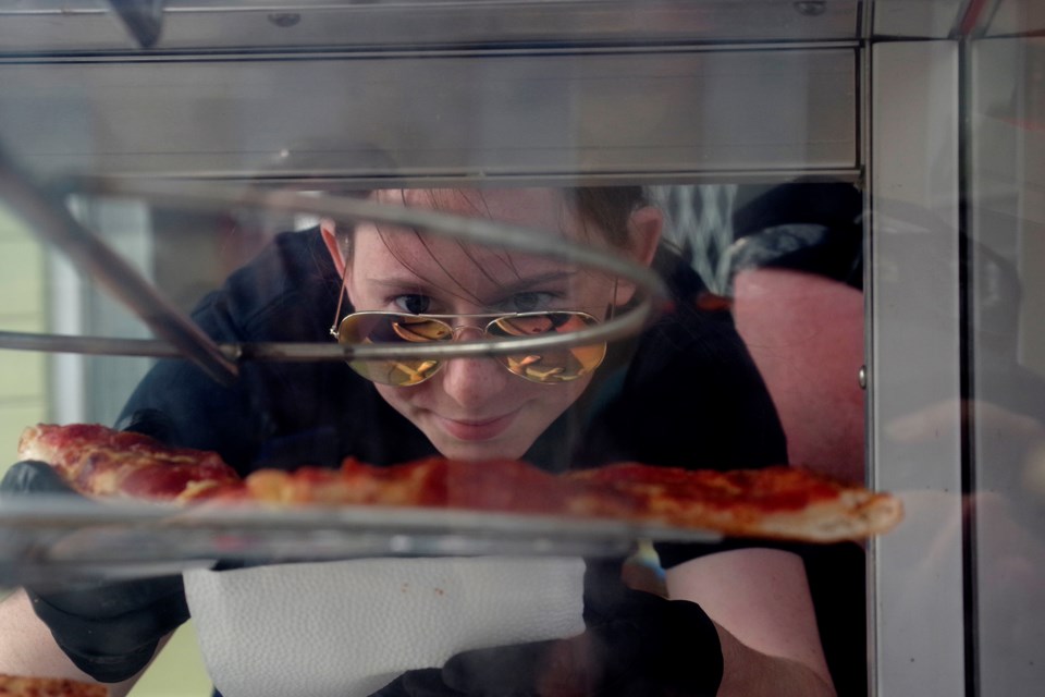 Marissa Mongelluzzo reaches for a slice of hot Papa Vince pizza for one of the hungry visitors to the downtown student and community welcome event. Bob Liddycoat / Thorold News