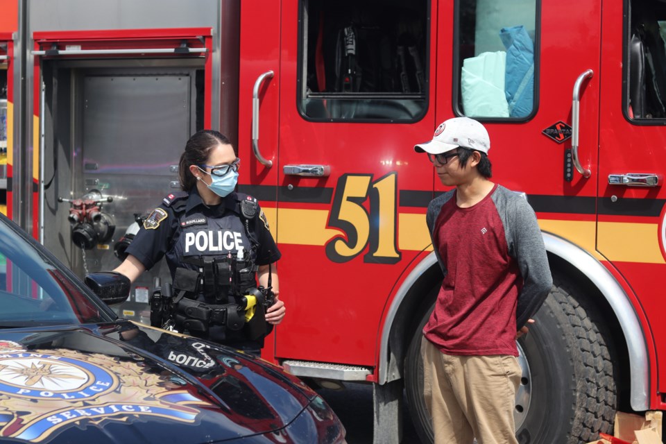 Pikangikum First Nation member Chandler Suggashie with a Const. Caroline Rouillard during a Touch-a-Truck event held Monday.