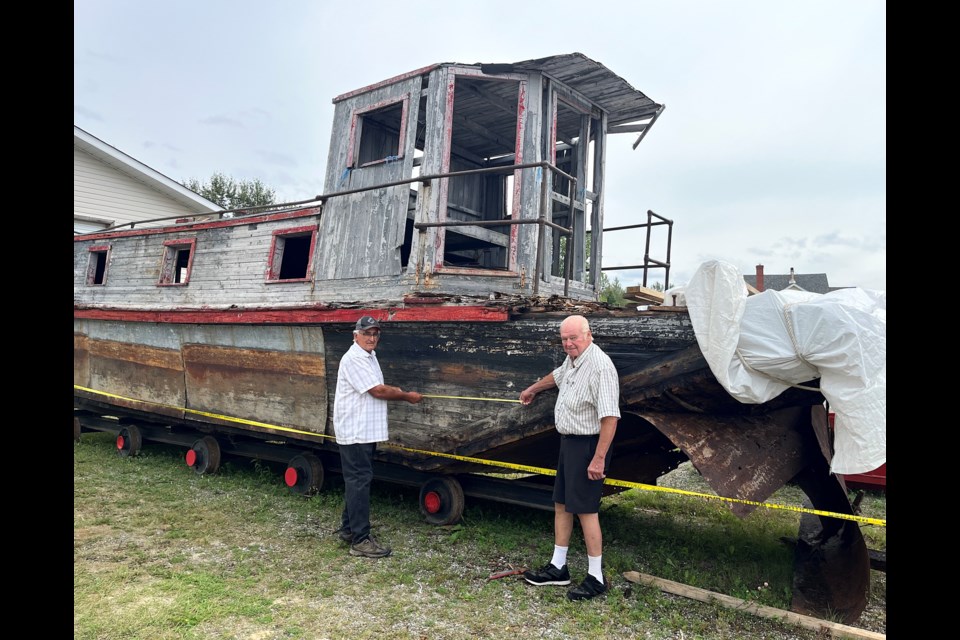 Rheal Dupuis, left, and Roy Saari take measurements of the alligator boat being restored by the Connaught and District Historical Society.