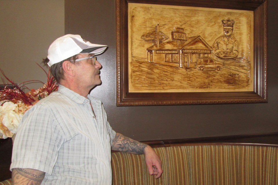 Andre Ouellet, owner of Don’s Pizzeria and Christopher’s Coffee House, looks at a framed wood carving of his father, the founder of Don’s. Ouellet has plans to amalgamate the two businesses, offering customers an expanded menu and a unique dining experience. Wayne Snider for TimminsToday