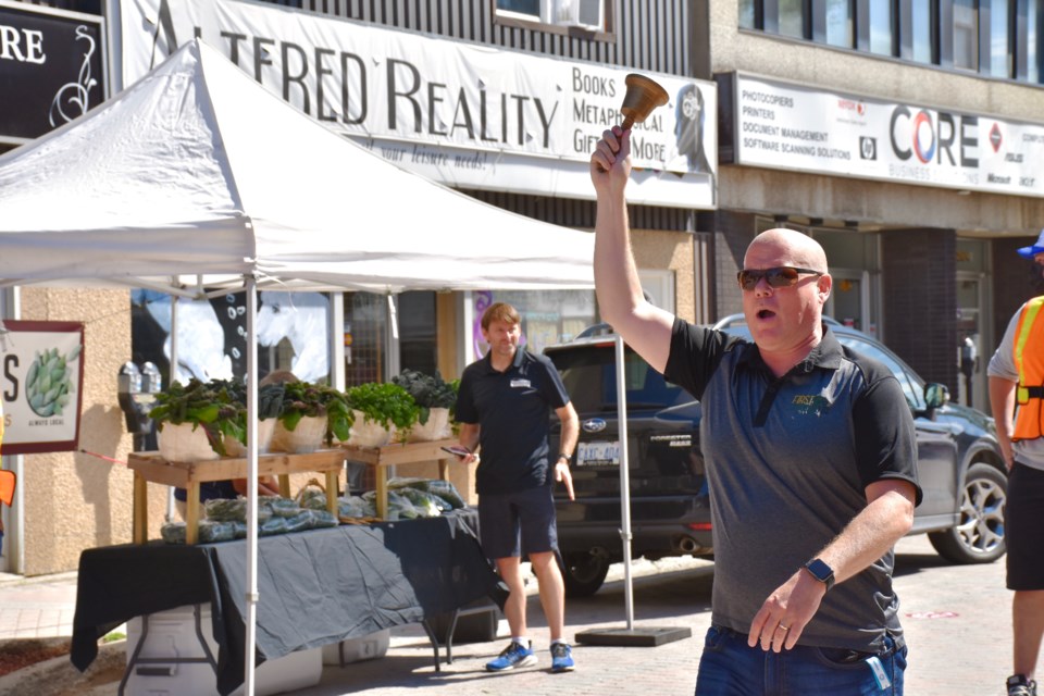 Downtown Timmins BIA chair Jamie Roach rings the bell telling vendors they can start selling for the first 2020 Urban Park Market. Maija Hoggett/TimminsToday