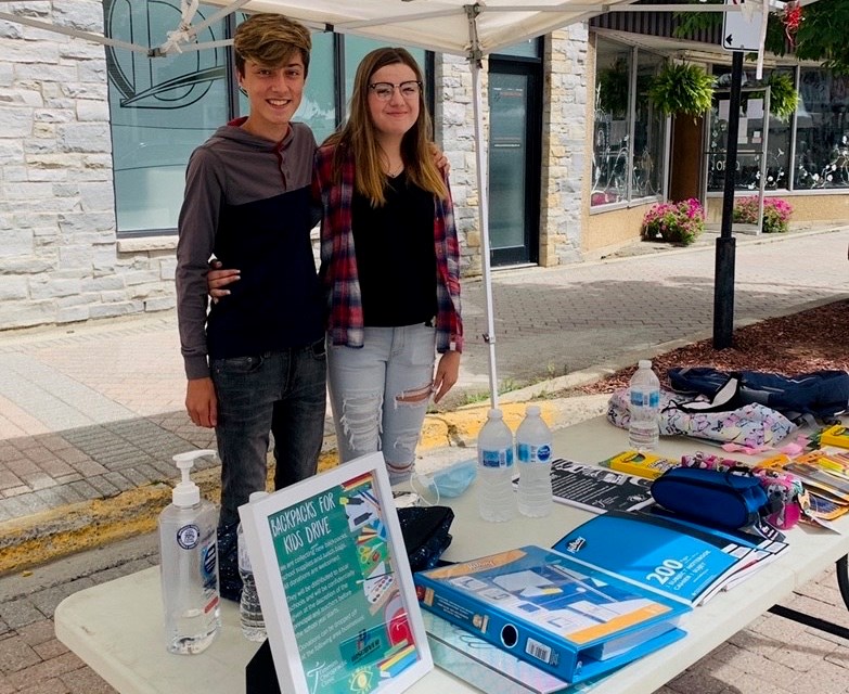 Students Noah Dmytrow and Abby Pilon collect backpacks for the program at the Downtown Timmins Urban Market. Supplied photo