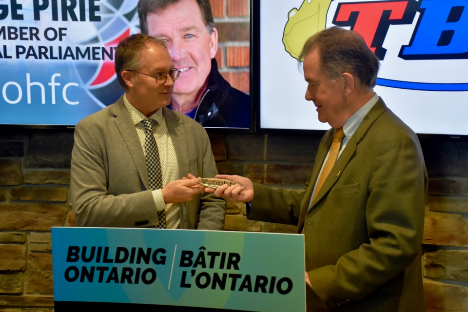 The Bucket Shop's business optimization lead Jamie Pouw shows Timmins MPP George Pirie the first item they made with a new water jet cutting table.
