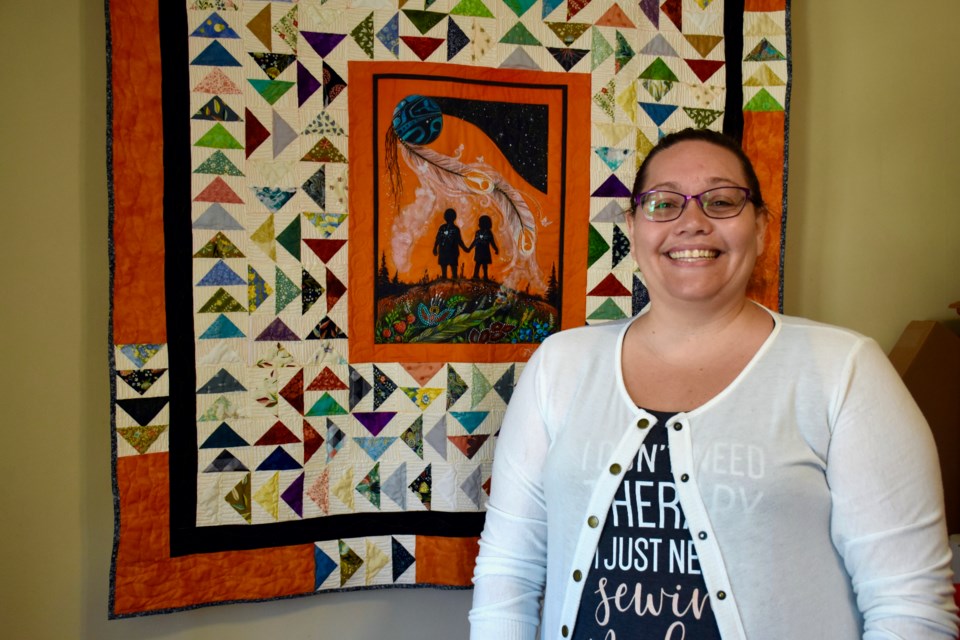 Quilts for Survivors founder Vanessa Génier with a quilt she designed featuring 215 geese that she hopes to gift to the British Columbia First Nation when she visits the area later this month.