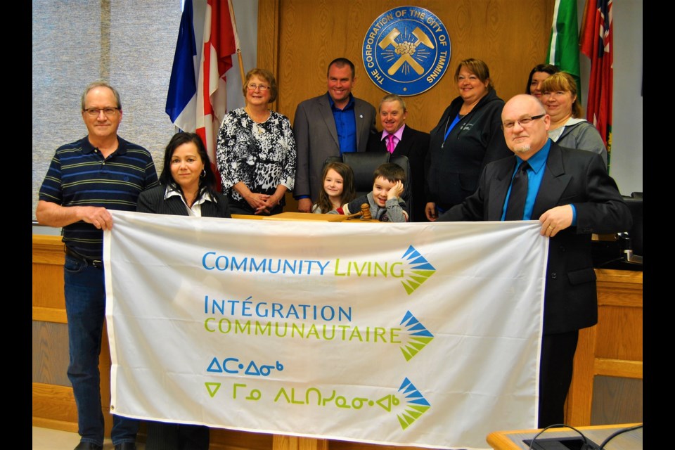 Mayor Steve Black along with Community Living staff and supporters celebrate May as Community Living Month in Timmins. Top row from left to right: Veronica Farrell, director; Mayor Steve Black, Dan Crowley, self-advocate, Lisa Lamarche, resource teacher, Sarah Raymond, parent, Cathy Courville, resource teacher; the children are Jase Darby and Dessa Darby. Front Row holding the flag from left to right: Robert Tremblay, President, Johanne Rondeau, Exective Director, Manuel St. Jean, Support Worker. Frank Giorno for TimminsToday.