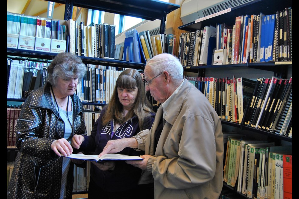 Rudolphe Labelle (right) and friends leaf through a book on genealogy at the new created Rudolphe Labelle Genealogy Collection . Frank Giorno for TimminsToday