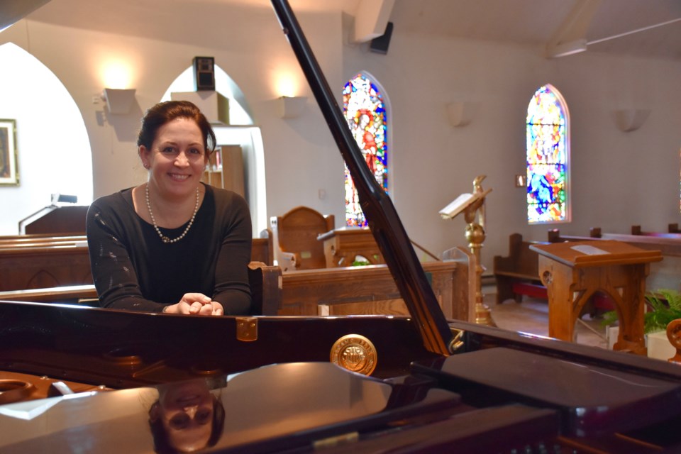 Nicola Alexander with the grand piano recently acquired for St. Matthews Cathedral in Timmins. Maija Hoggett/TimminsToday
