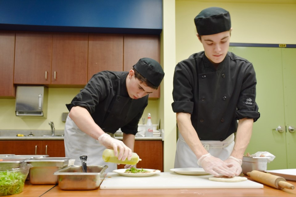 Students prepare pizza for guests at Timmins High and Vocational School's Triptych Blues event, which packed the Timmins Public Library. Along with the fresh eats, there was artwork, live music, and more. Maija Hoggett/TimminsToday