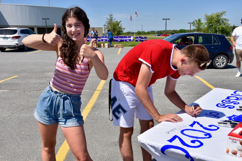 Kennedy Verbeek and Owen Haggerty add their names to the banner for 2020 graduates at Timmins High. Maija Hoggett/TimminsToday
