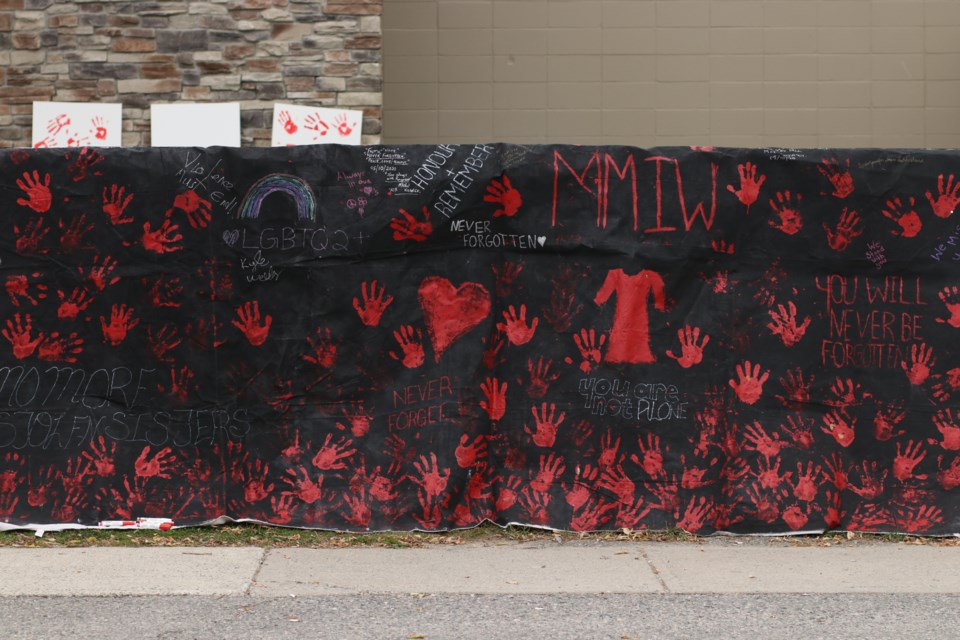 A canvas covered in red hand prints, baring messages about missing and murdered indigenous women, girls and 2SLGBTQIA people.