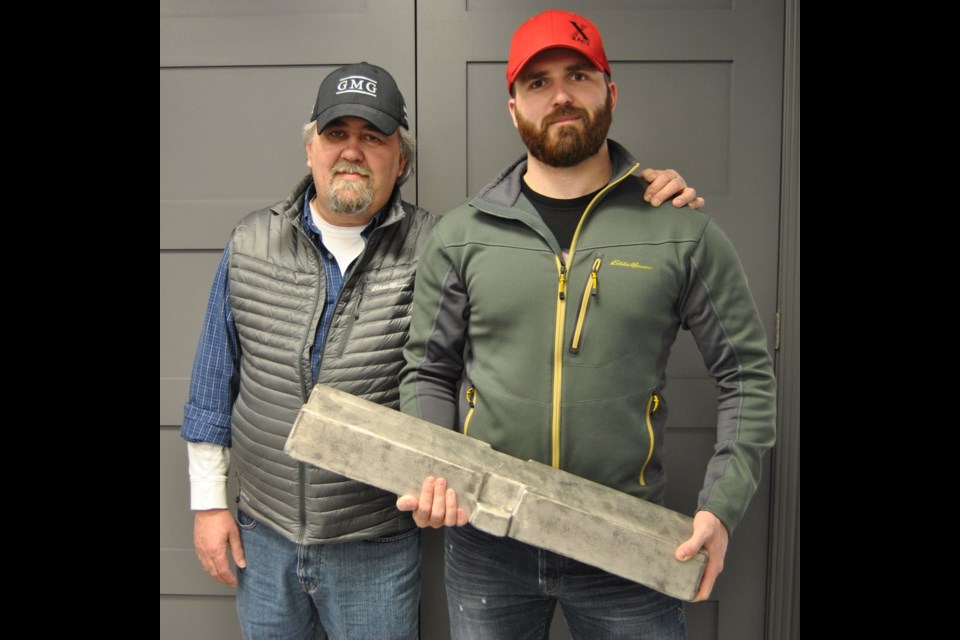 William Quesnel, Chair of General Magnesium Corporation (left) with son Ryan (right) holding a plastic bar made with magnesium in a photo taken in December, 2014. Photo by Frank Giorno