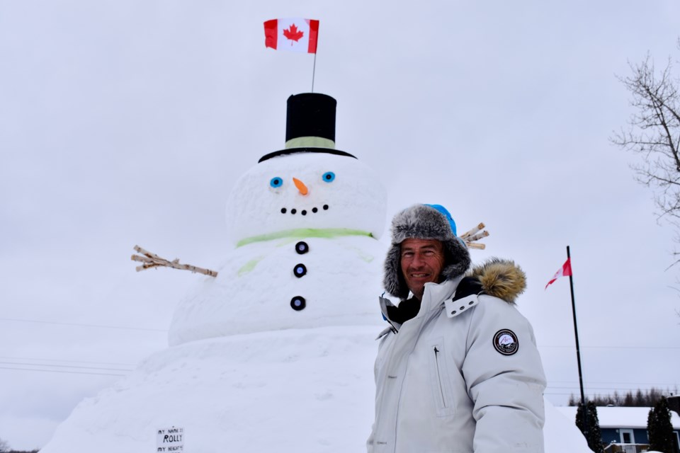 Michel Campeau with Rolly, the 45-foot snowman he built on Carrigan Road in Timmins. People are invited to stop by to meet Rolly, snap a photo and drop off donations for area food banks. 
