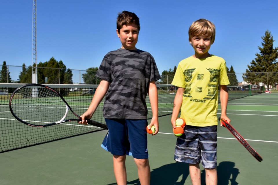 Hayden Bourgon, 12, and Ethan Harris, 10, are honing their tennis skills at the Timmins Tennis Club's free youth lessons at the Pine Street South courts. Maija Hoggett/TimminsToday
