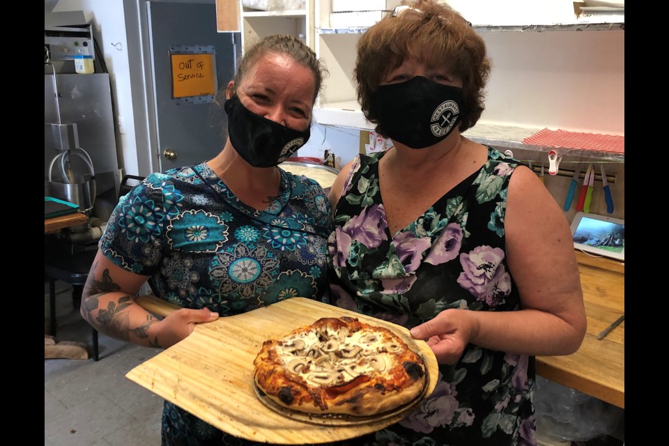 Restaurant Nadeau owner Julie Therrien (left) and her mother Chantel Ross display a freshly made pizza. Therrien invested in a pizza oven and the restaurant now offers homemade pizza.
