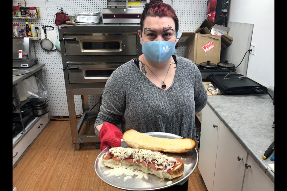 Melissa Michaud, assistant manager at Sue's Variety, displays a freshly made pizza sub.
