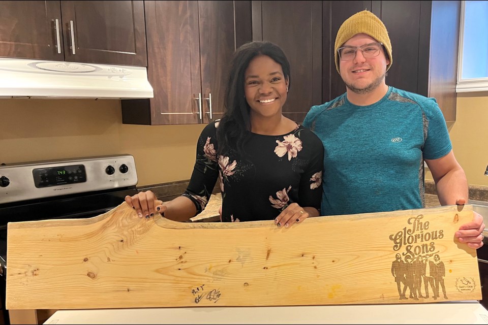 Sweet & Salty Charcuterie owners Noemie and Eric Rodrigue display the charcuterie board they made to serve to The Glorious Sons at Rock on the River. The band loved the food and design so much, they signed the board as a souvenir for the couple.