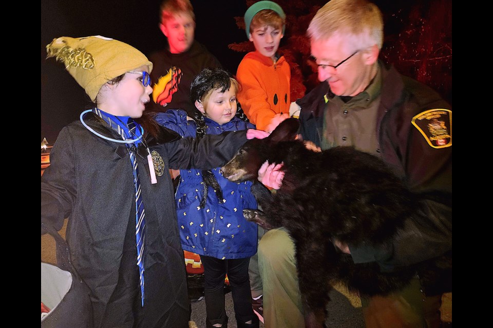 Daisy Pettifer, left and Alexis LeBlanc, centre, were two of several children out trick or treating Halloween Night who stopped to pet a black bear cub that was captured in a busy east-end Westlock neighbourhood. The bear cub is being moved to a wildlife rehab centre in southern Alberta and will be released into the wild next spring.   