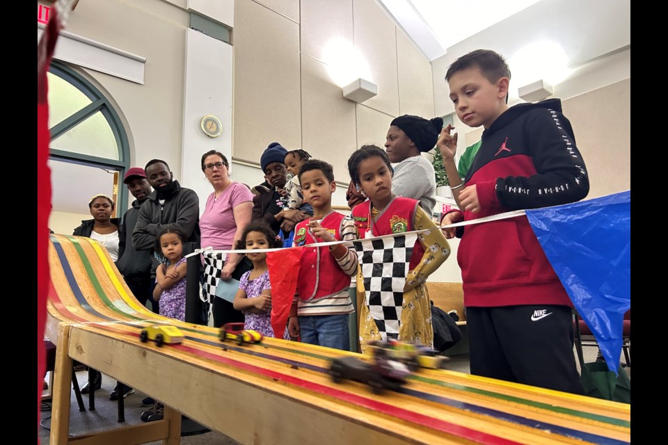 A row of spectators watch as cars race along a wooden track inside the Westlock Gospel Chapel on March 14 during the 2024 AWANA Grand Prix. This is a yearly event in which children and adults build pre-made cars and race for prizes. AWANA itself is a non-profit organization that puts on fun activities for children while teaching them about the Bible.