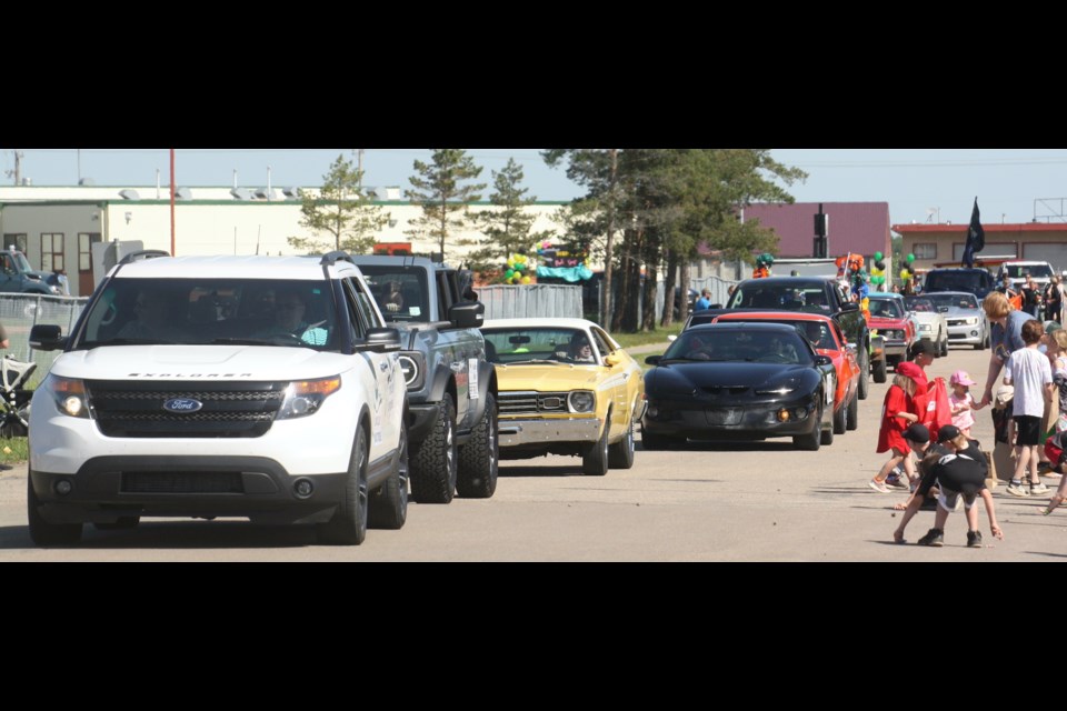 While a line of cars rolls by, children rush to pick up the candy thrown out by the parade participants in the Clyde Summer Solstice Festival on June 22.
