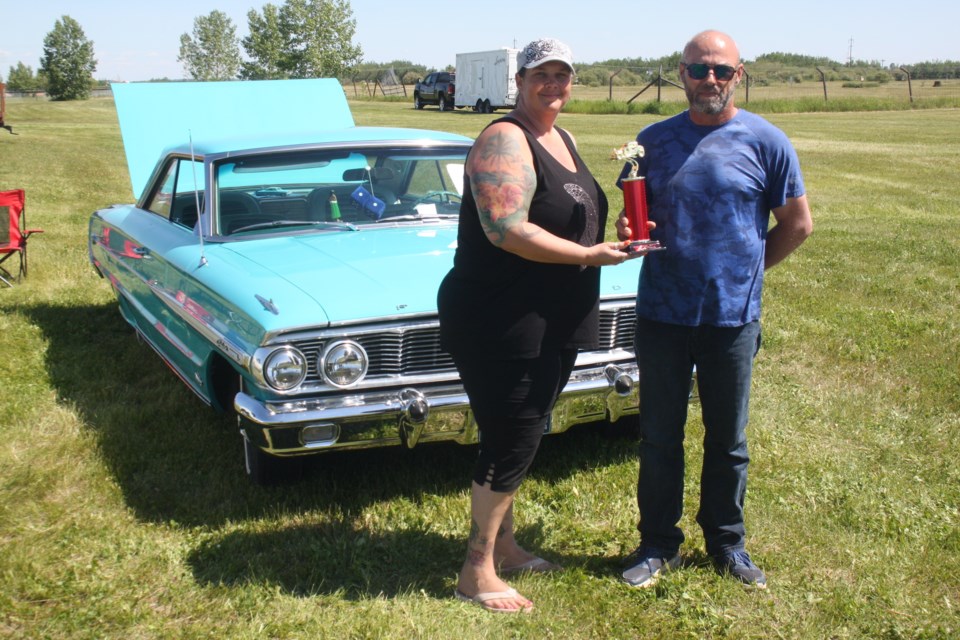 Summer Solstice Festival organizer Kelly Patry hands over the People's Choice award to Tony Hnatiuk for his entry in the car show, a 1969 Galaxie 500. This was the second year in a row he won the trophy, incidentally.