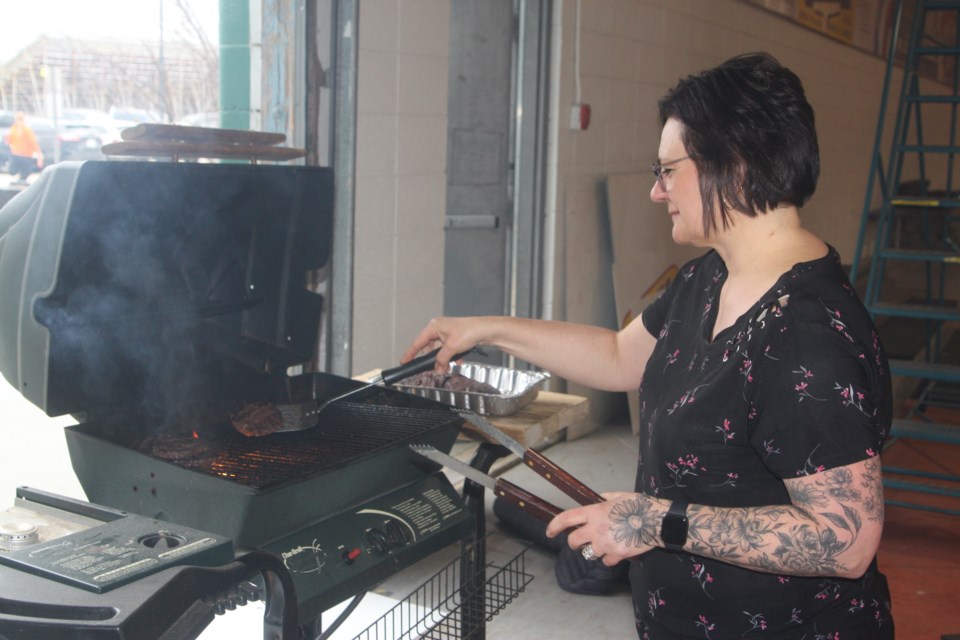 Bruinella Mitchell fries hamburgers for the volunteers using a grill set up inside the Westlock Curling Club. In addition to hamburgers and hot dogs, the event also served up free drinks, chips and ice cream.