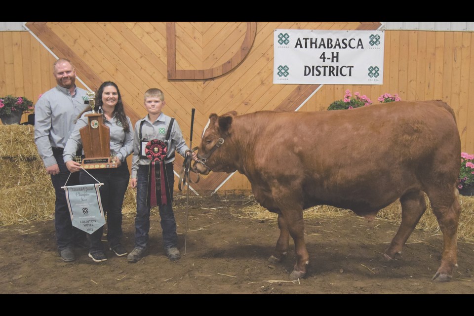 Mark Splane of the Boyle 4-H Beef Club holds his award-winning Interclub Grand Champion Market Steer while his trophy and banner are held by Stephanie Splane, with David Splane behind.