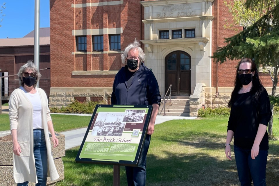 Athabasca Heritage Society chair Margaret Anderson, heritage society member Mike Gismondi and Town of Athabasca CAO Rachel Ramey unveiled the new sign May 21 for the Brick School. The old signage was weathered and was the first of many of the 36 signs around Athabasca to be replaced over the coming months.