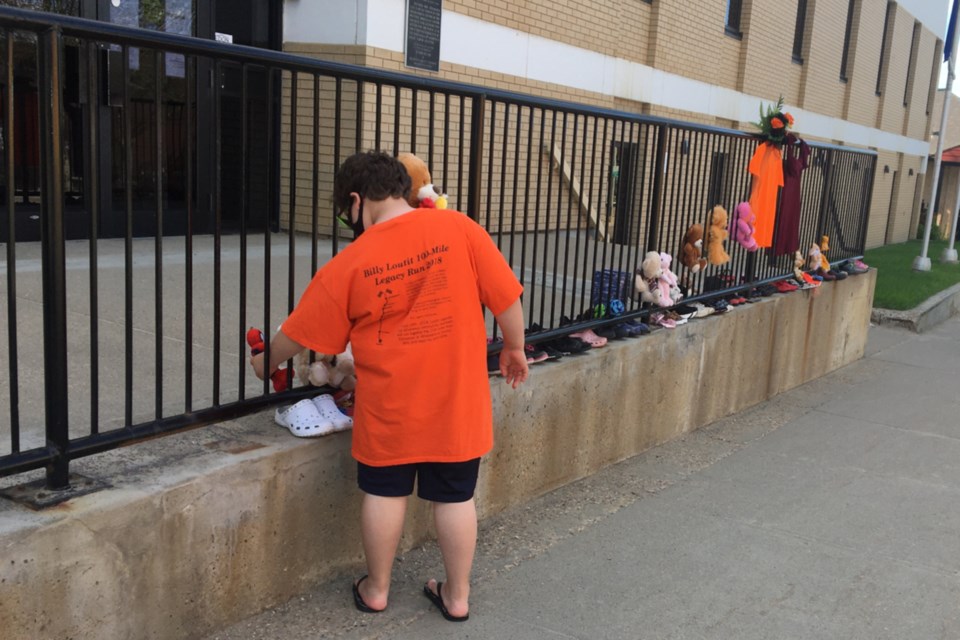 Grade 3 student Isaiah Bouchier placed shoes and a stuffed animal outside the Athabasca Provincial Building May 31 in memory of 215 Indigenous children whose unmarked graves were recently discovered at a former residential school in British Columbia. The impromptu memorial was shared on social media encouraging people to take shoes and other items down in the hope of having 215 items.