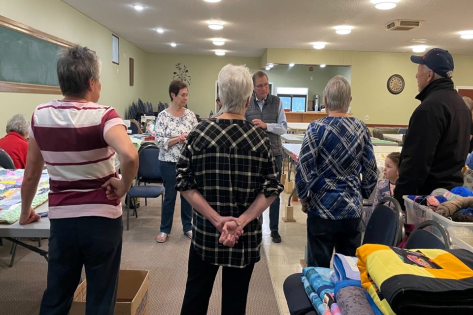 (L-R) Eleanor Staszewski keeps working on a quilt while Audrey Shapka, Marie Stelmach, and Quilting for Humanity Society president Yvonne Doroshenko listen to former Alberta premier Ed Stelmach talk about how his foundation is helping the people of Ukraine during the war. Eileen Fawcett and Town of Athabasca mayor Rob Balay with granddaughter Charlotte were also listening intently. 