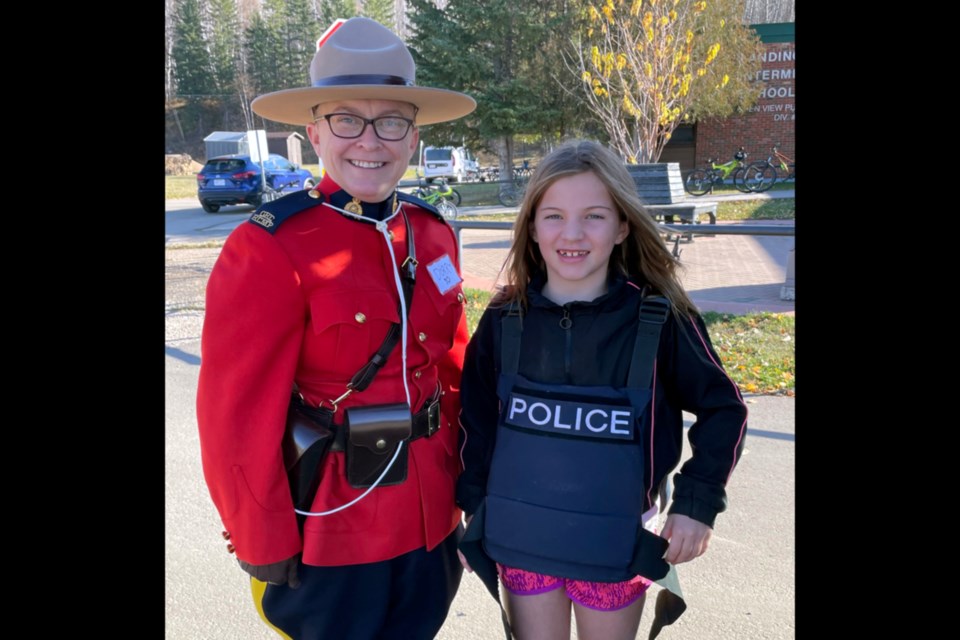 Cst. Rachel Dorrington with the Athabasca RCMP was one of many people representing various jobs at Landing Trail Intermediate School (LTIS) Oct. 14. Grade 4 student Anja Allen got to find out just how heavy the body armour is as well as check out the inside of the RCMP vehicles.