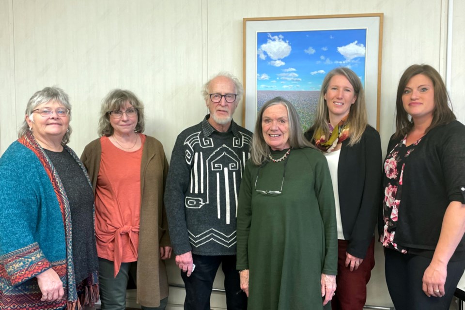 Town of Athabasca Coun. Edie Yuill, archivist Margaret Anderson, artist Sylvain Voyer, librarian Cynthia Graefe, library board chair Nadine Byers, and Athabasca County Coun. Kelly Chamzuk gather in front of one of the two paintings donated to the Alice B. Donahue Library and Archives by Charles Van Duren in memory of his wife Judith. A small event was held Oct. 28 dedicating the two paintings. 