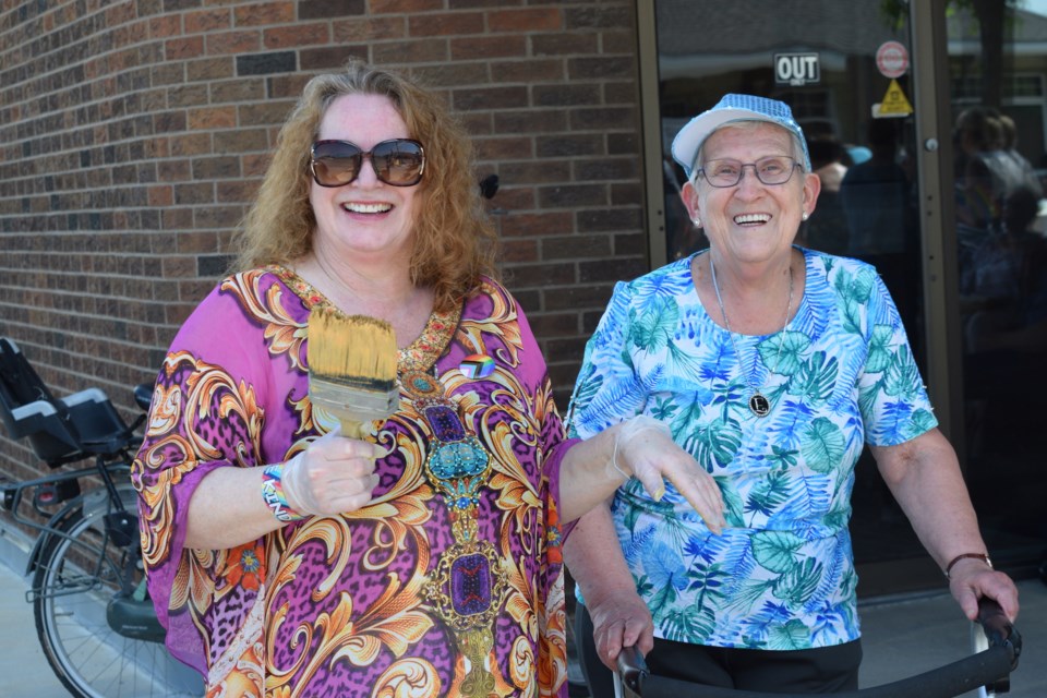 Barb Churchill and Elaine Toma pose for a picture during Barrhead's Pride flag crosswalk painting event on June 4. Churchill came to help paint, while Toma, who could not physically help, came to support the effort.